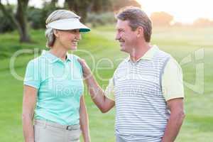 Golfing couple smiling at camera on the putting green