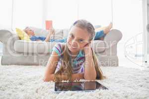 Portrait of happy girl using digital tablet on rug at home