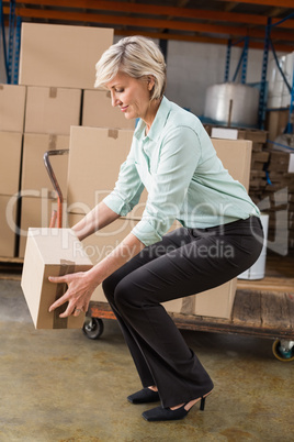 Warehouse manager picking up cardboard box