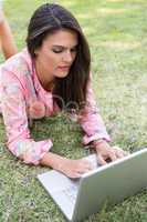 Pretty brunette using laptop in park