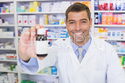 Handsome pharmacist showing medicine bottle