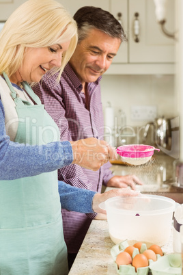 Happy blonde preparing dough with husband