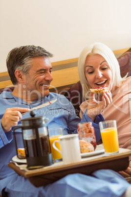 Happy mature couple having breakfast in bed