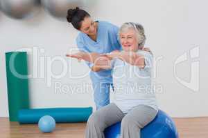 Instructor assisting senior woman in exercising