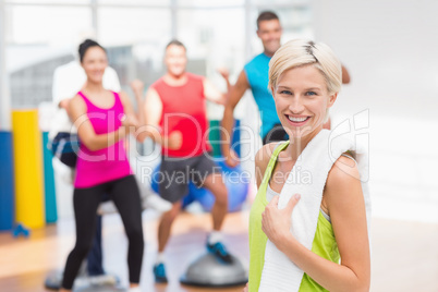 Portrait of happy woman holding towel at gym
