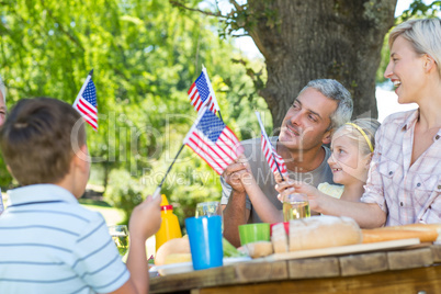 Happy family having picnic and holding american flag