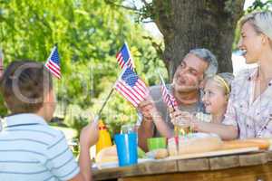 Happy family having picnic and holding american flag