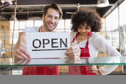 Smiling team posing behind the counter with open sign