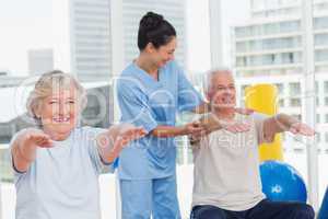 Trainer assisting senior couple in exercising