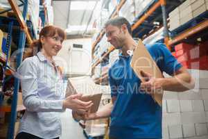 Delivery man passing parcel to warehouse manager
