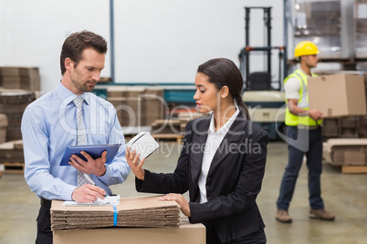 Warehouse managers holding box and looking at tablet pc