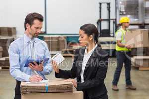 Warehouse managers holding box and looking at tablet pc