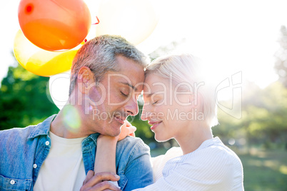 Cute couple holding balloons at the park