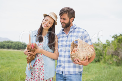 Happy farmers holding chicken and eggs