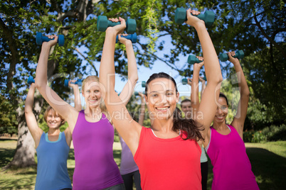 Fitness group lifting hand weights in park