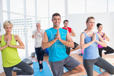 People practicing tree pose in fitness studio