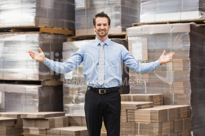 Smiling warehouse manager with hands out