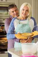 Mature blonde holding fresh pie with husband hugging her