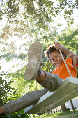 Happy little boy on a swing in the park