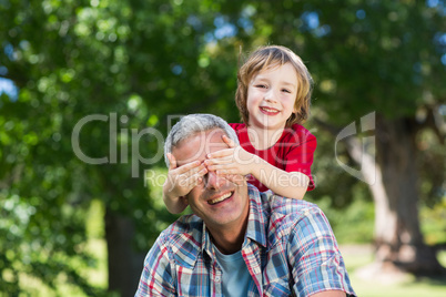 Happy little boy hiding his fatherss eyes with his hands