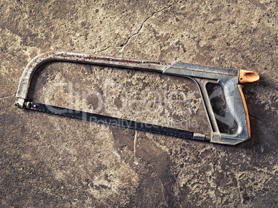 old hacksaw on concrete grungy background