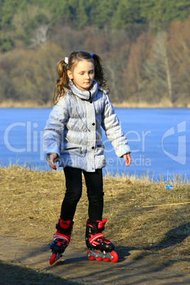 young girl goes in roller skates on the ground