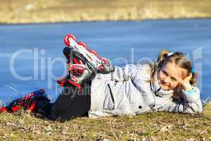 young girl in roller skates lays on the ground