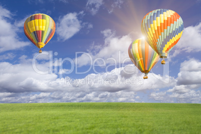 Hot Air Balloons In Beautiful Blue Sky Above Grass Field