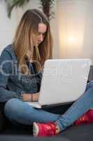 Teenager sitzt mit Laptop auf dem Sofa