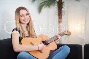Mädchen mit Gitarre sitzt auf einem Sofa