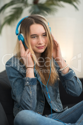 Mädchen sitzt mit Kopfhörer auf dem Sofa