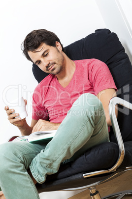 Man Sitting on Chair with Book and a Drink