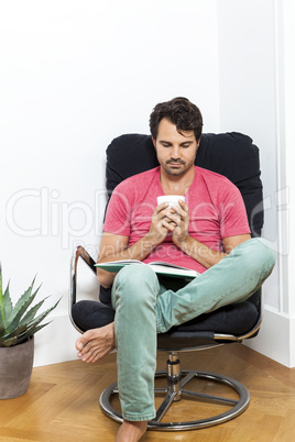 Man Sitting on Chair with Book and a Drink