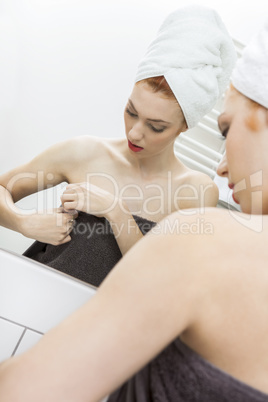 Woman From Shower Looking her Face at the Mirror
