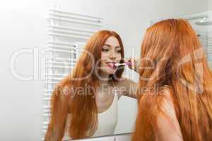 Woman Brushing her Teeth in Front a Mirror