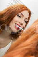 Woman Brushing her Teeth in Front a Mirror