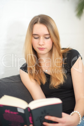 Teenager liest auf dem Sofa ein Buch