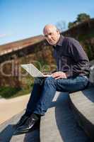 Man sitting on a bench using a laptop