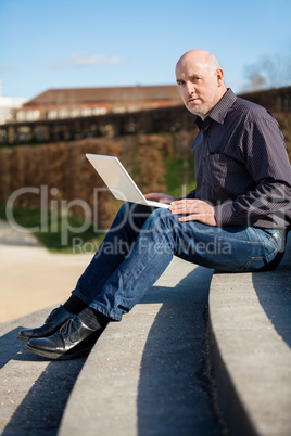 Man sitting on a bench using a laptop