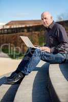 Man sitting on a bench using a laptop