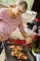 Attractive blond woman barbecuing meat