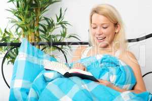 Blonde Frau liest im Bett ein Buch