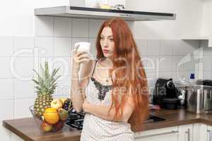 Serious Blond Woman Holding A Glass at the Kitchen