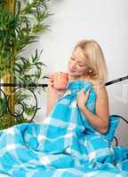 Blonde Frau genießt ersten Kaffee im Bett