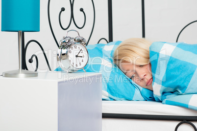Blonde Frau liegt schlaflos im Bett