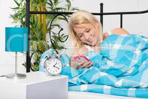 Frau liegt nachts im Bett simst mit Handy