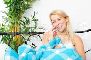 Frau liegt im Bett und telefoniert mit Handy