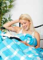 Blonde Frau liest im Bett ein Buch