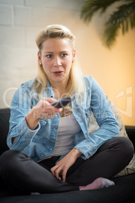 Frau im Wohnzimmer mit Fernbedienung