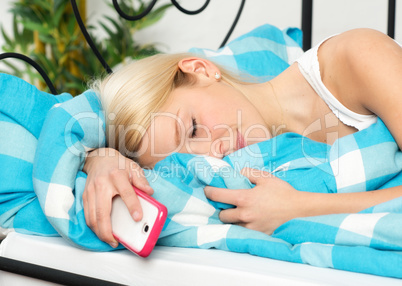 Frau mit Handy im Bett schläft